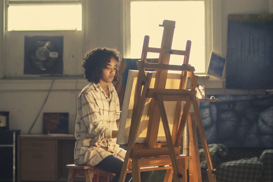 photo of woman painting in brown wooden easel