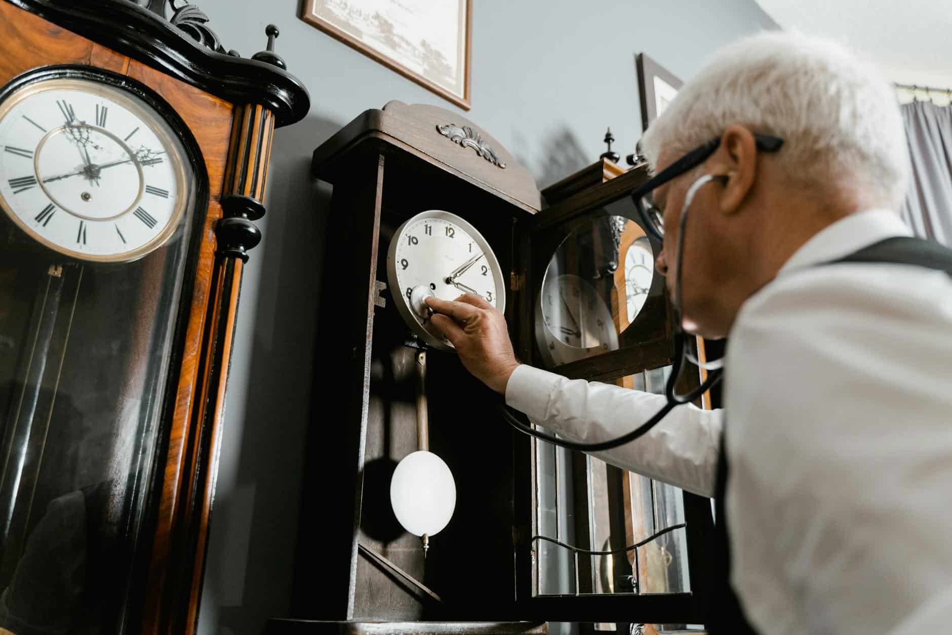 a man with white hair checking the vintage wall clock using stethoscope