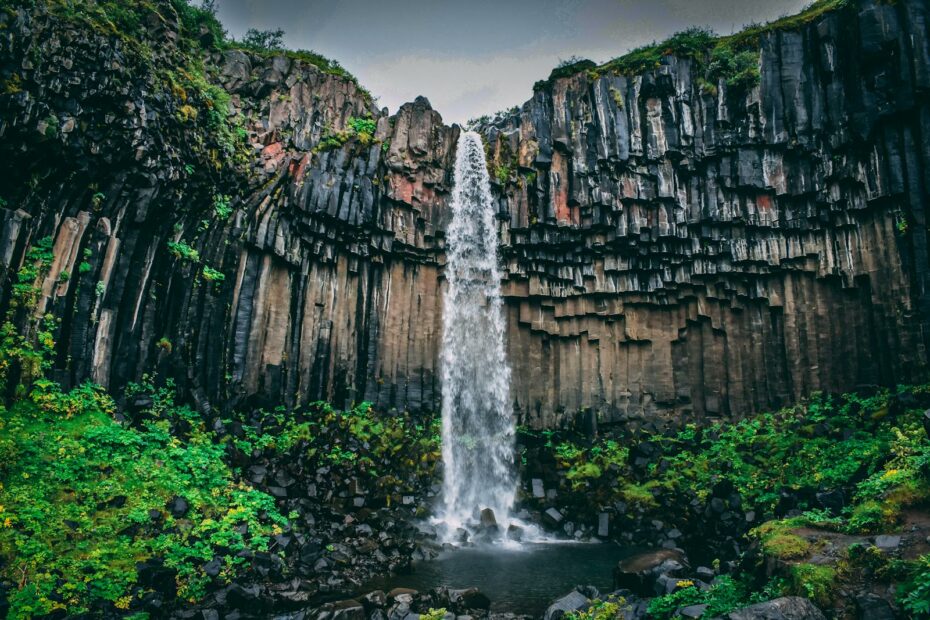 Captivating waterfall cascading over unique basalt columns surrounded by vibrant greenery.