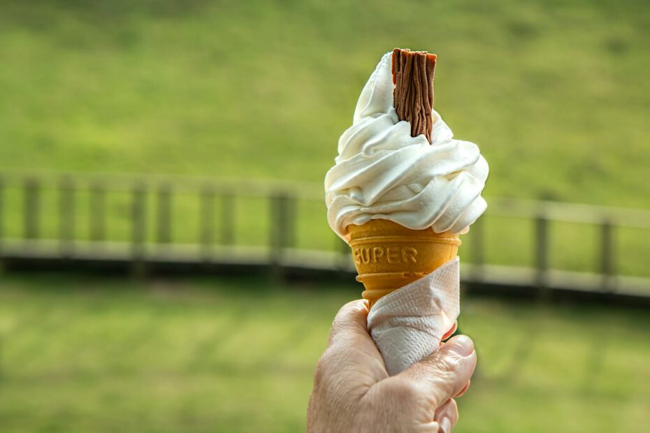 Enjoying a soft vanilla ice cream cone with a chocolate flake on a sunny day.