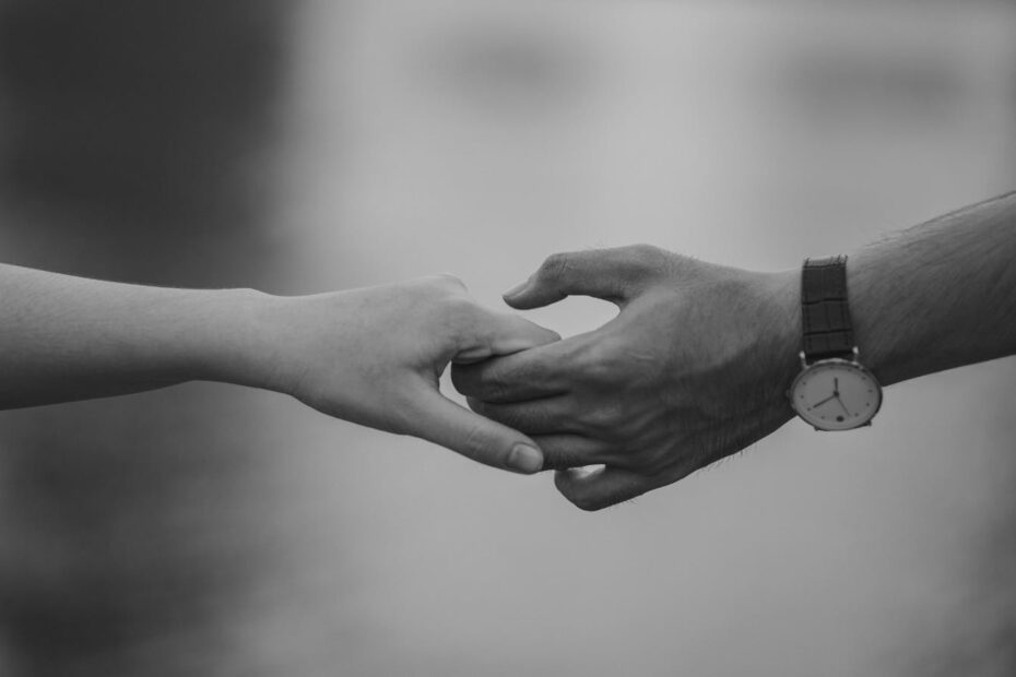 Monochrome image of two hands holding, symbolizing love and connection.