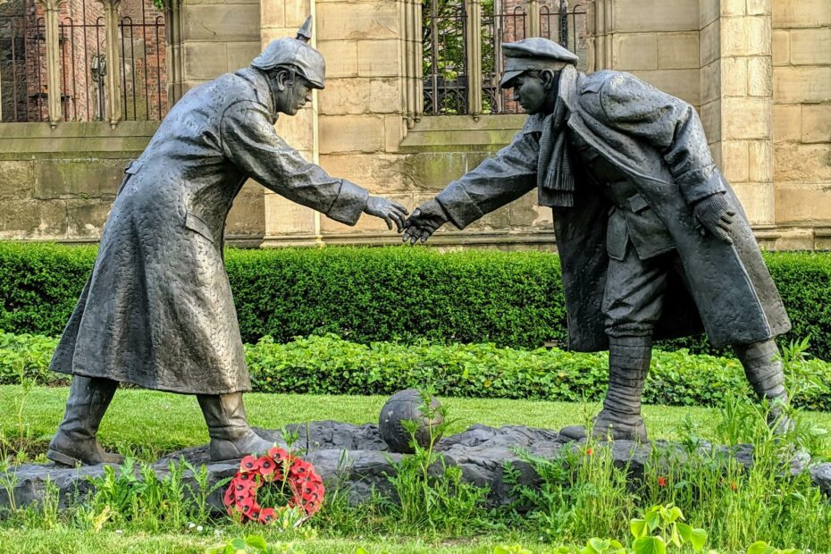 Stone sculpture depicting soldiers shaking hands during the WWI Christmas Truce in England.