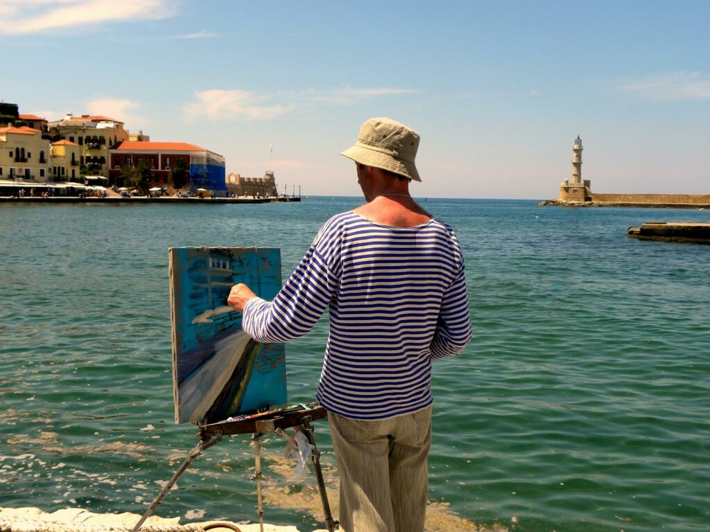 A painter capturing the scenic view of Chania lighthouse by the sea, Greece.