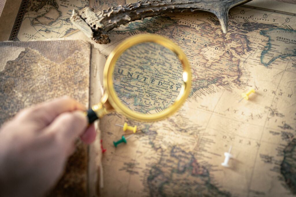 Hand holding magnifying glass over vintage USA map, capturing exploration and discovery theme.