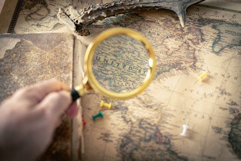 Hand holding magnifying glass over vintage USA map, capturing exploration and discovery theme.