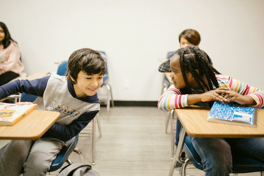 Children of diverse backgrounds chatting in a lively classroom setting.