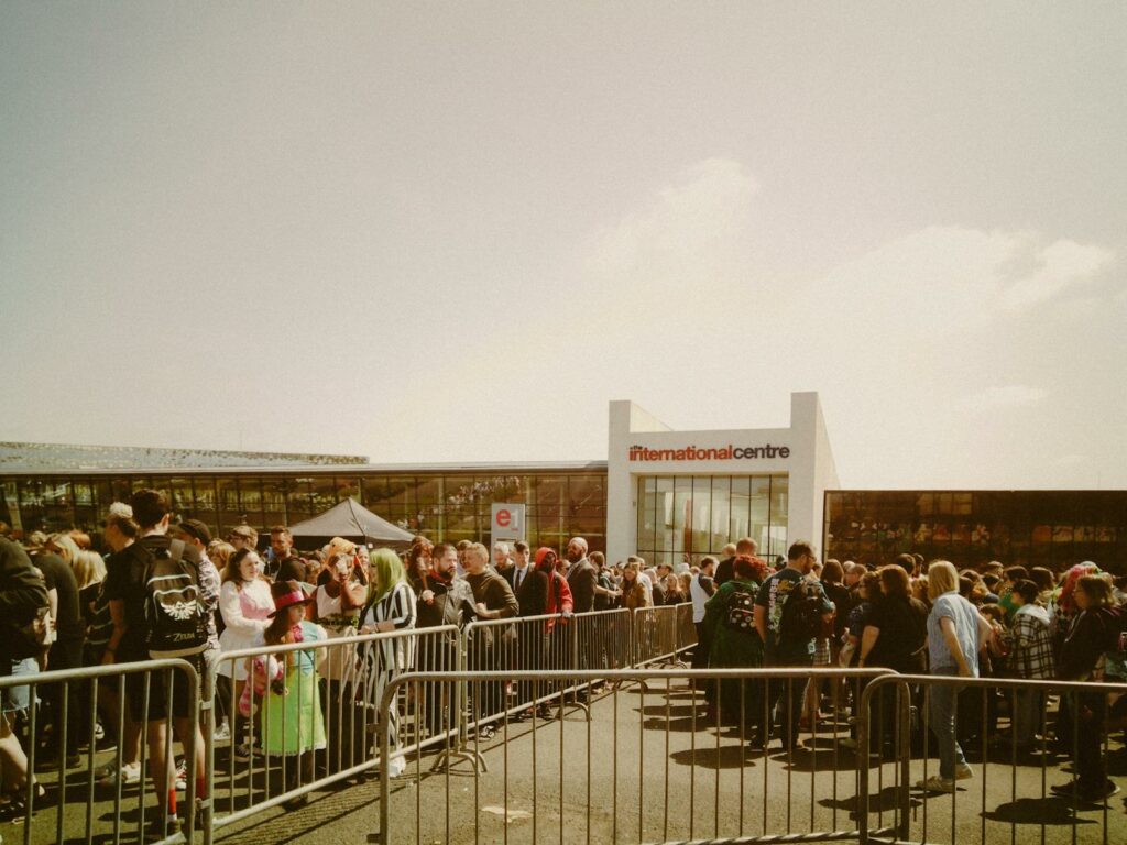 Large crowd gathering outside the International Centre under sunny skies.